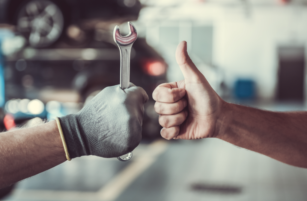 A service technician holding a wrench next to someone giving a thumbs up